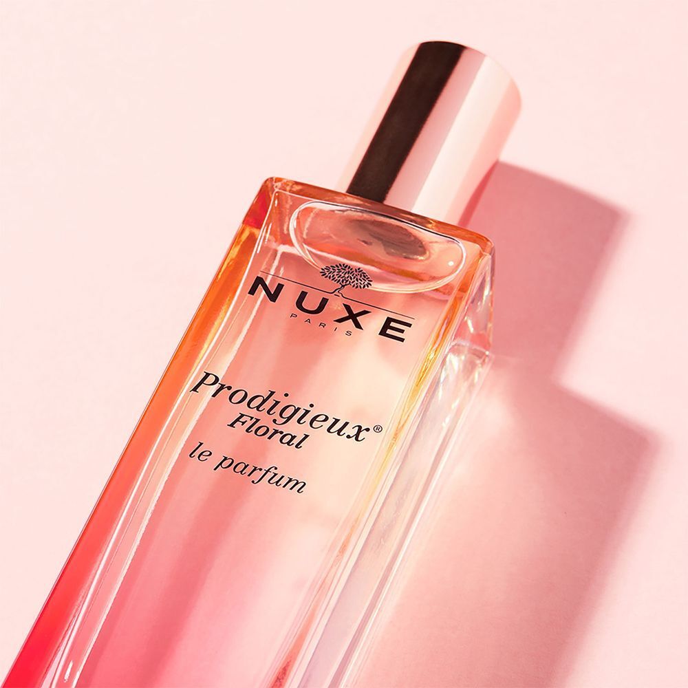 Primo piano di un flacone di Nuxe Prodigieux Floral Le Parfum su sfondo rosa.
