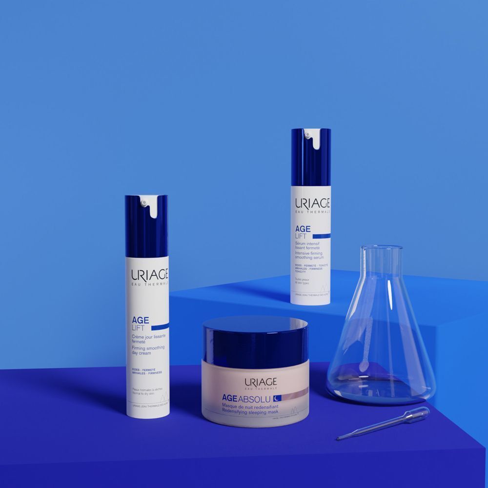 Prodotti Uriage Age Lift, inclusi crema giorno e Age Absolu, disposti con attrezzature di laboratorio.