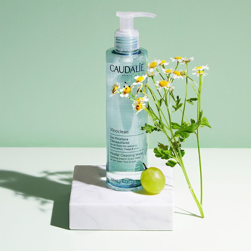 Flacone di acqua micellare Caudalie Vinoclean con dispenser a pompa, uva e fiori di camomilla.