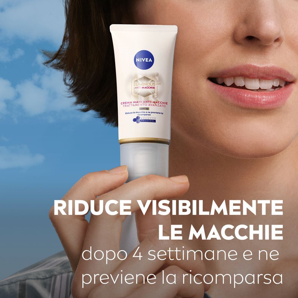 Una donna tiene un tubo di crema mani Nivea Luminous630 con SPF 15. Il testo afferma che le macchie sono visibilmente ridotte.