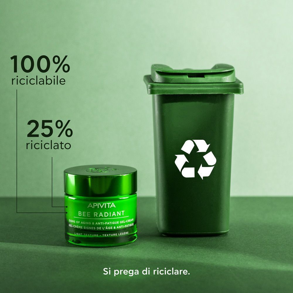 Vaso verde APIVITA BEE RADIANT crema viso accanto a un bidone verde con simbolo di riciclo.