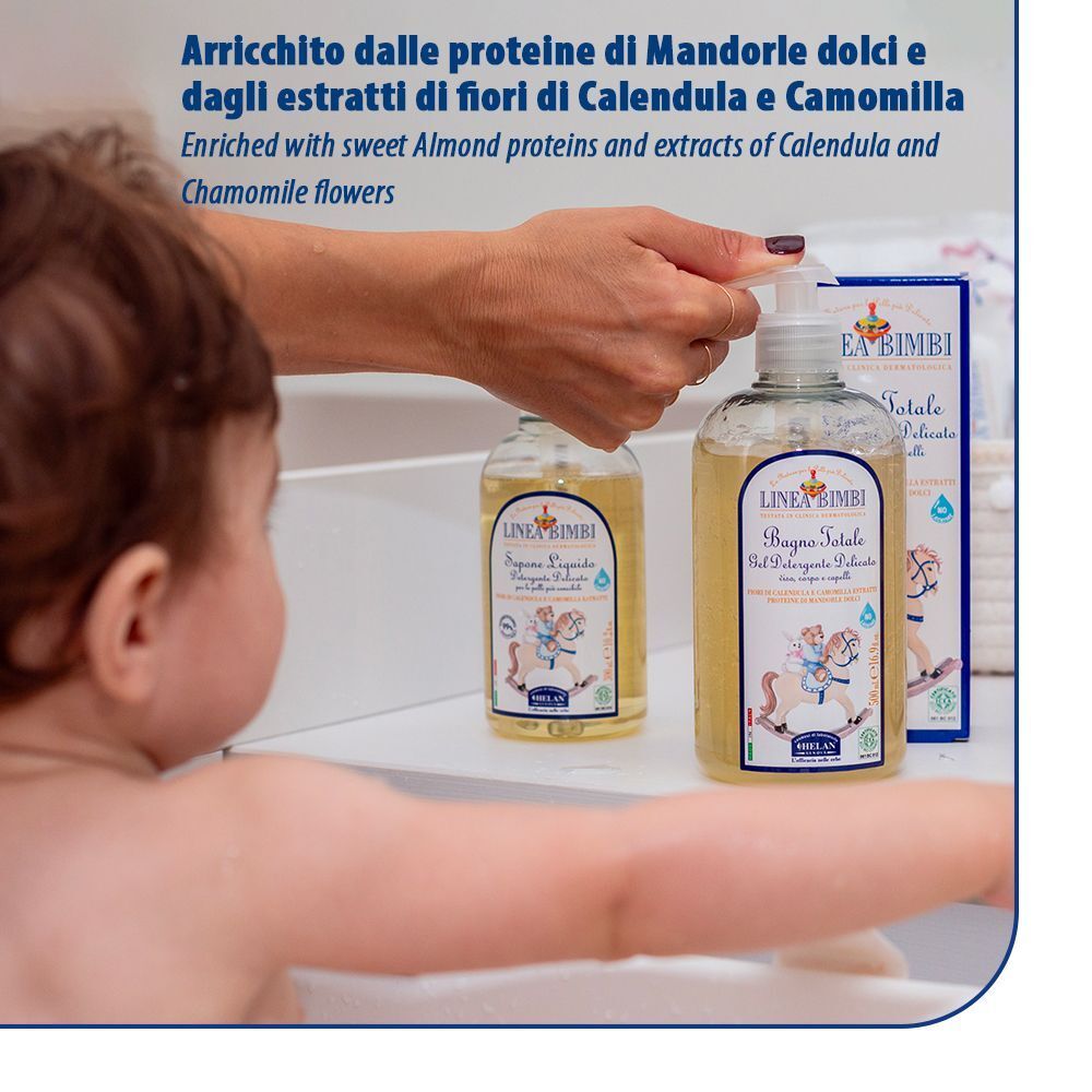 Una persona lava un bambino nella vasca da bagno, due flaconi Helan LINEA BIMBI Bagno Totale sullo sfondo.