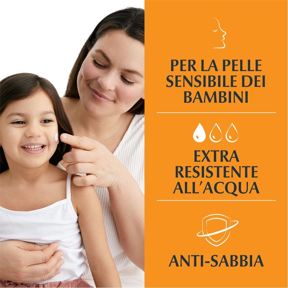 Madre applica crema solare su bambina sorridente. Testo: Per la pelle sensibile dei bambini, extra resistente all'acqua, anti-sabbia.