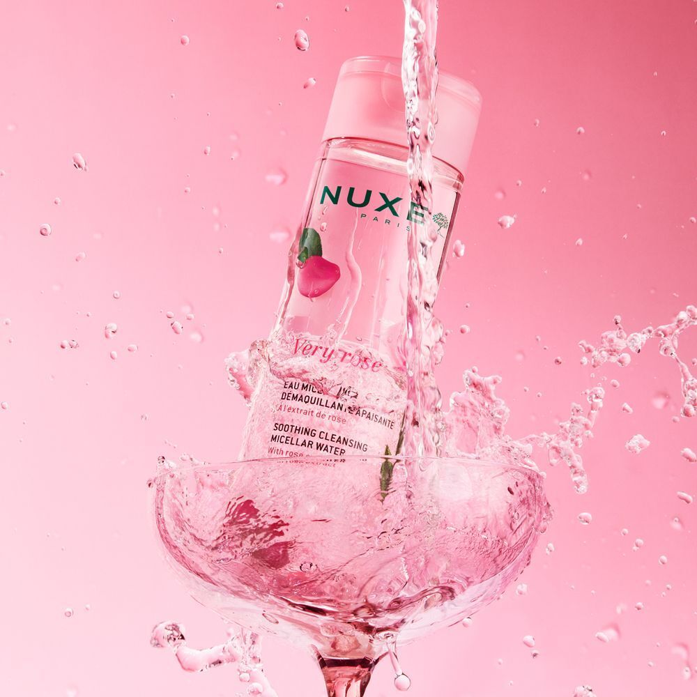 Nuxe Very Rose Acqua Micellare Lenitiva in un bicchiere con acqua spruzzata.
