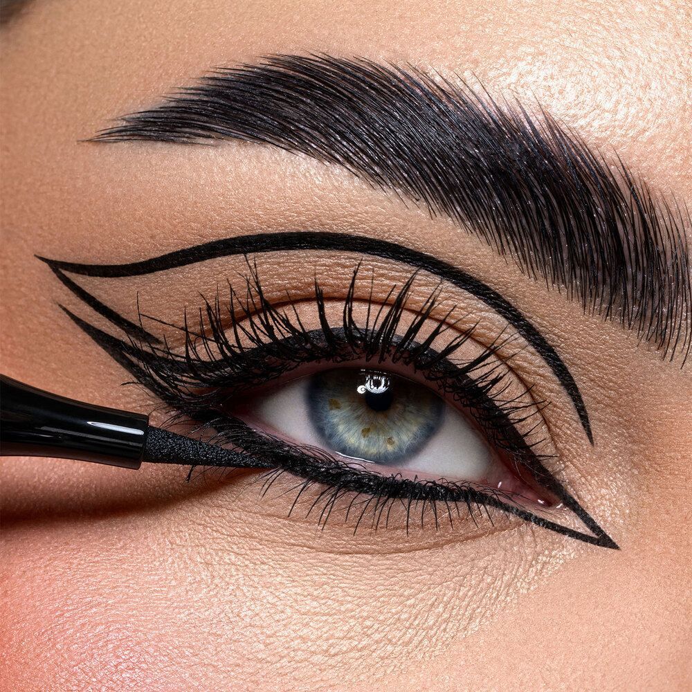 Primo piano di un occhio che riceve un tratto di eyeliner nero a punta fine per un look drammatico.
