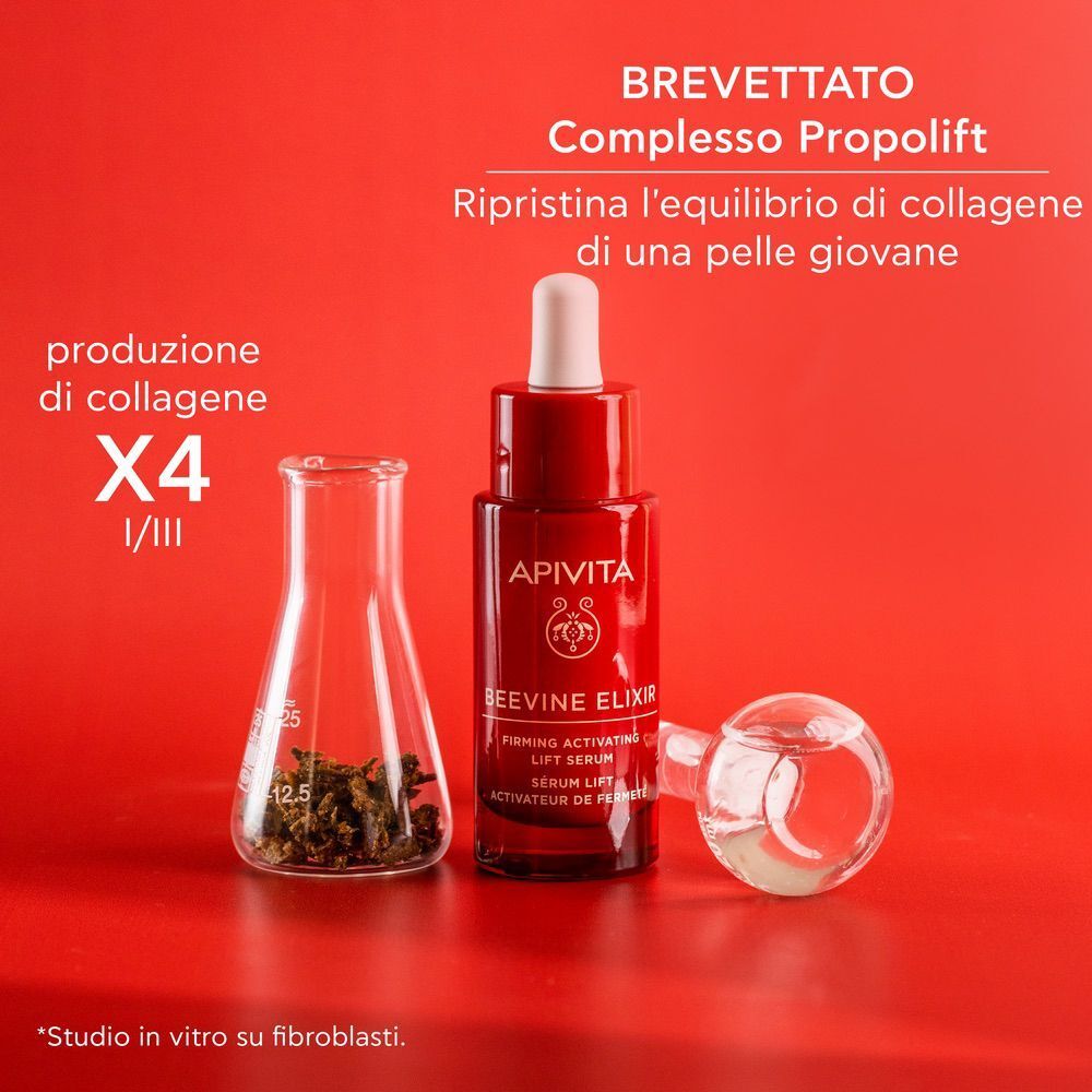 Flacone di siero Apivita Beevine Elixir accanto a un becher con granuli di propoli.