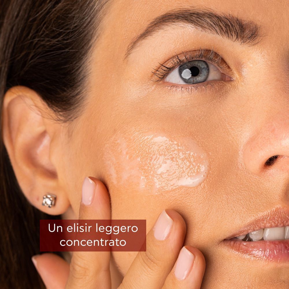 Una mano applica un elisir leggero e concentrato sulla pelle.