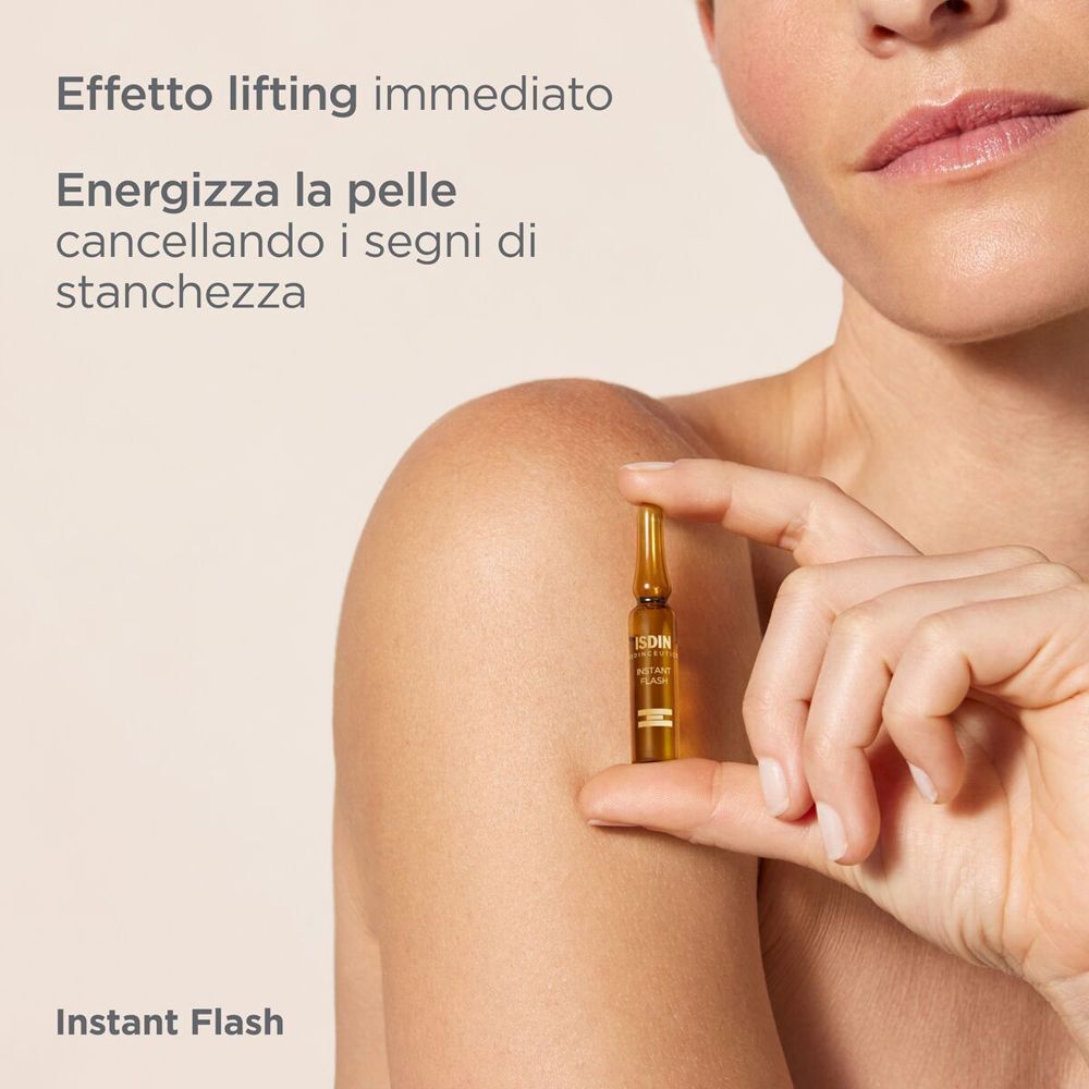 Una mano tiene un'ampolla ISDIN Instant Flash davanti a una spalla.