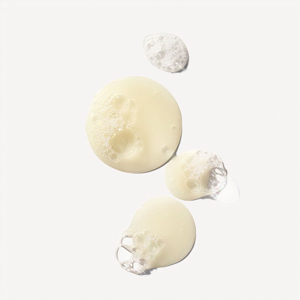 Gocce di shampoo giallo con schiuma su sfondo bianco.