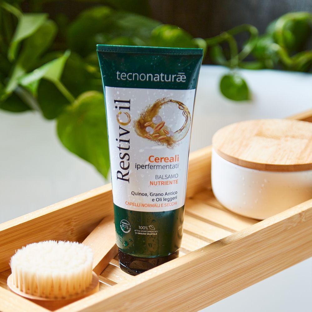 Un tubo Restivoil Tecnonaturae Balsamo Nutriente su un vassoio di legno con accessori da bagno.