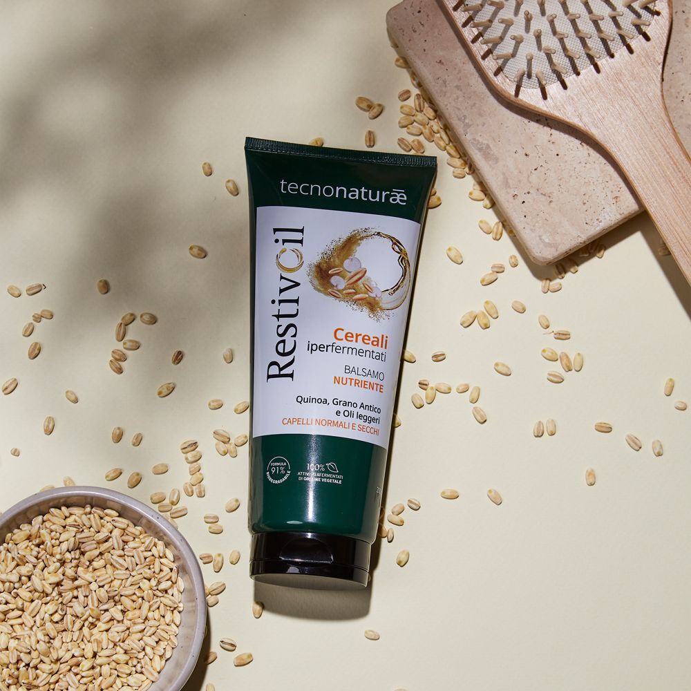 Un tubo Restivoil Tecnonaturae Balsamo Nutriente con chicchi di cereali e una spazzola per capelli.