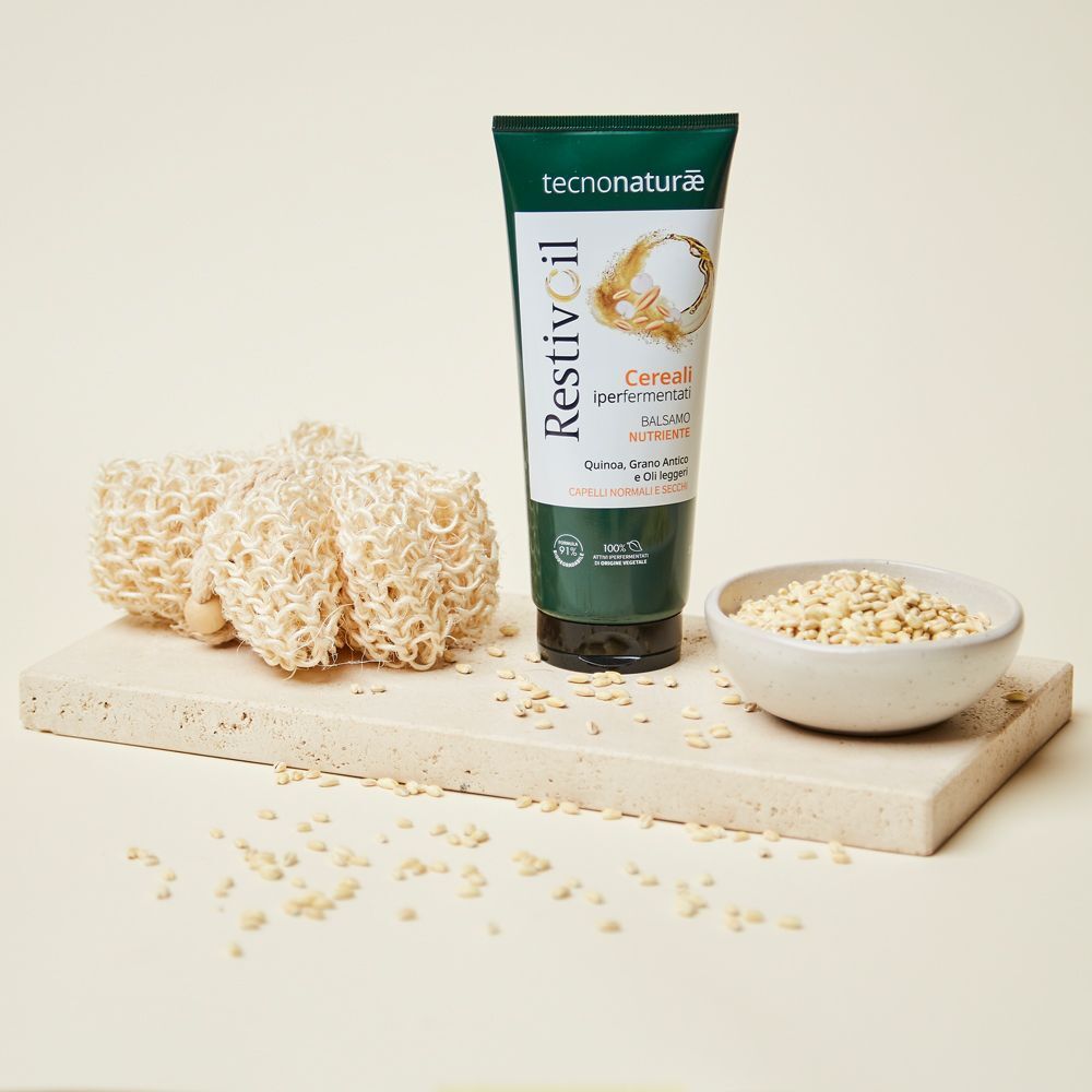Un tubo Restivoil Tecnonaturae Balsamo Nutriente con spugne di luffa e una ciotola di cereali.