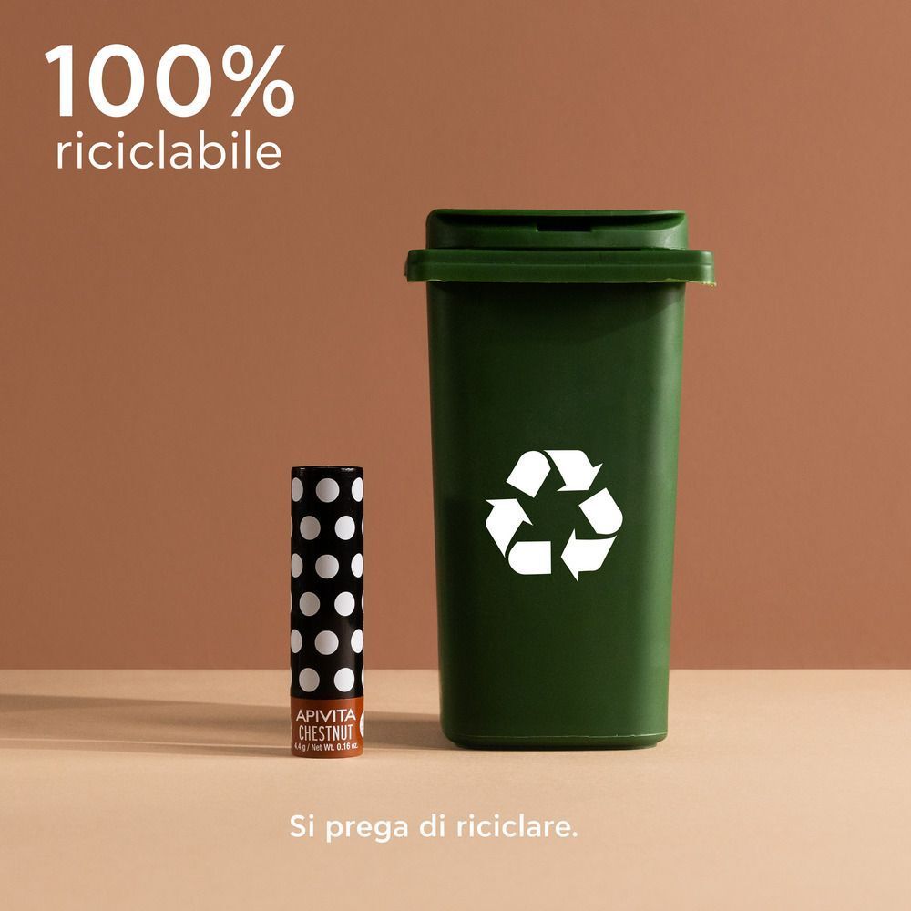 Balsamo labbra riciclabile al 100% accanto a un bidone della spazzatura verde.
