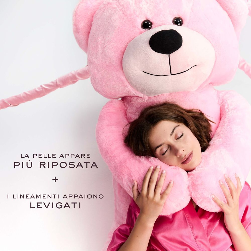Donna addormentata, abbracciata da un orsacchiotto, con testo sulla pelle riposata.