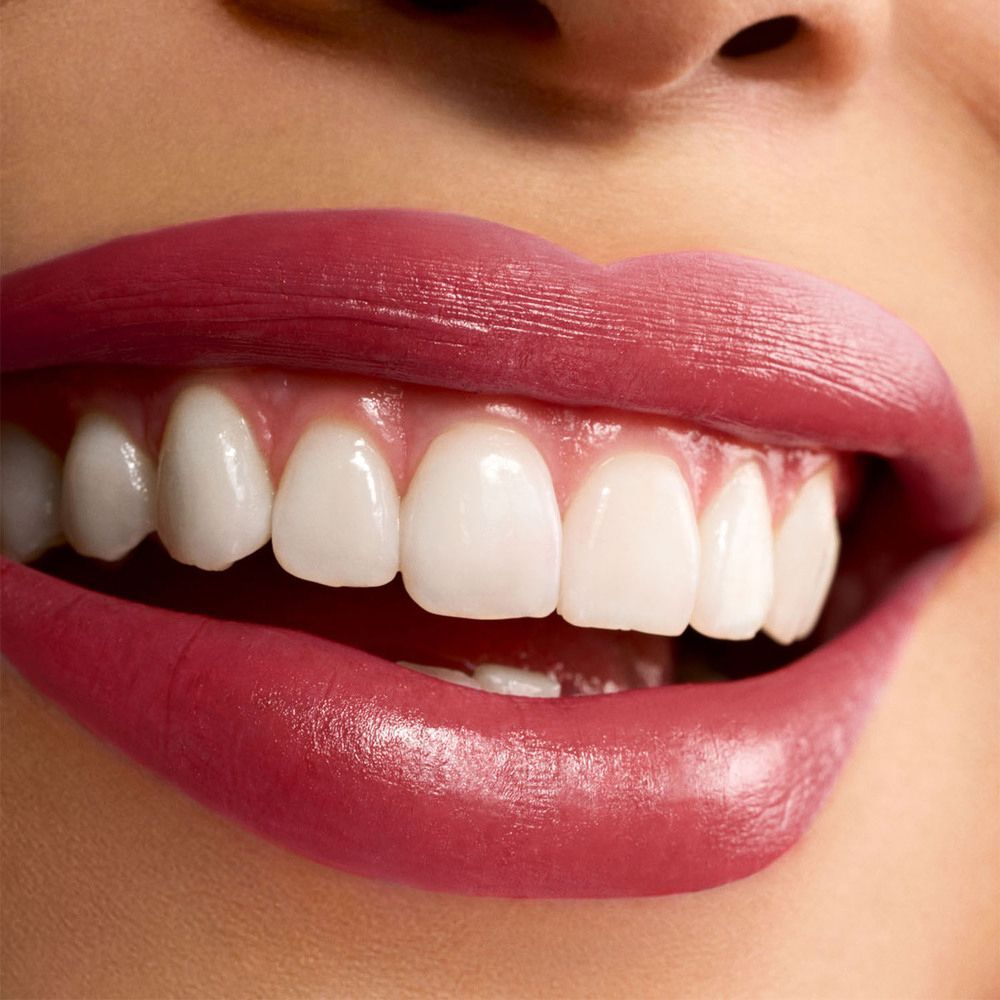 Primo piano di una bocca con labbra carnose, truccate con rossetto rosso ciliegia intenso.
