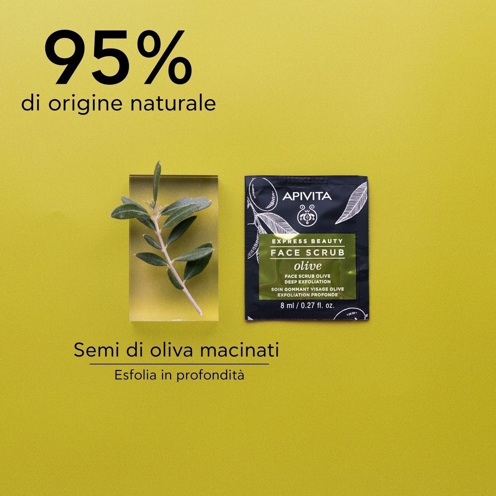 Una bustina singola di esfoliante viso APIVITA EXPRESS BEAUTY all'oliva accanto a un ramo d'ulivo.