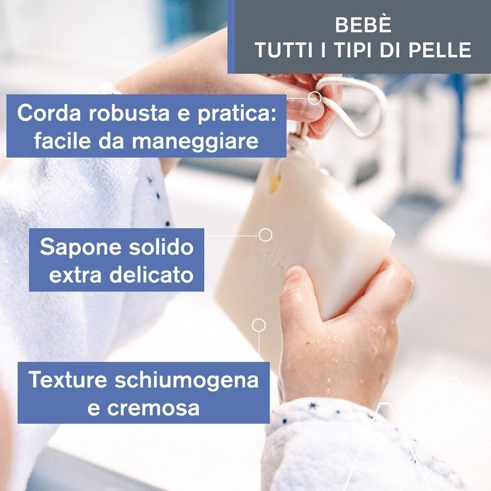 Mani che tengono Uriage Bébé 1a Crema Lavante Solida con cordino. Texture schiumogena.