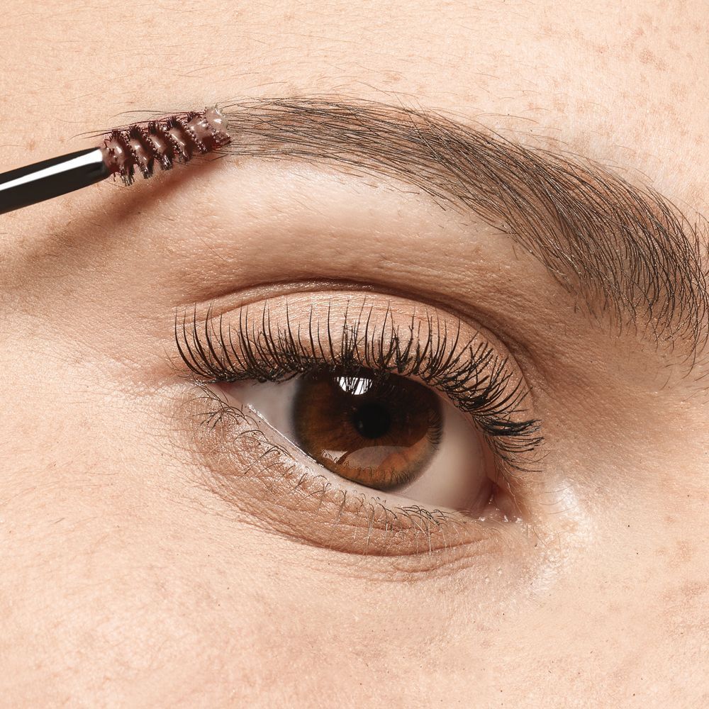 Primo piano di un applicatore che stende mascara su un sopracciglio.