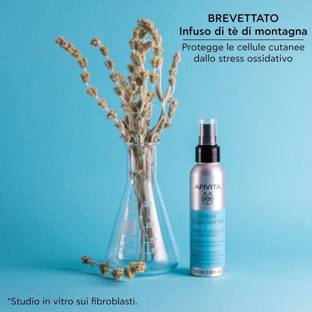Una donna si spruzza APIVITA Greek Mountain Tea Face Water sul viso.