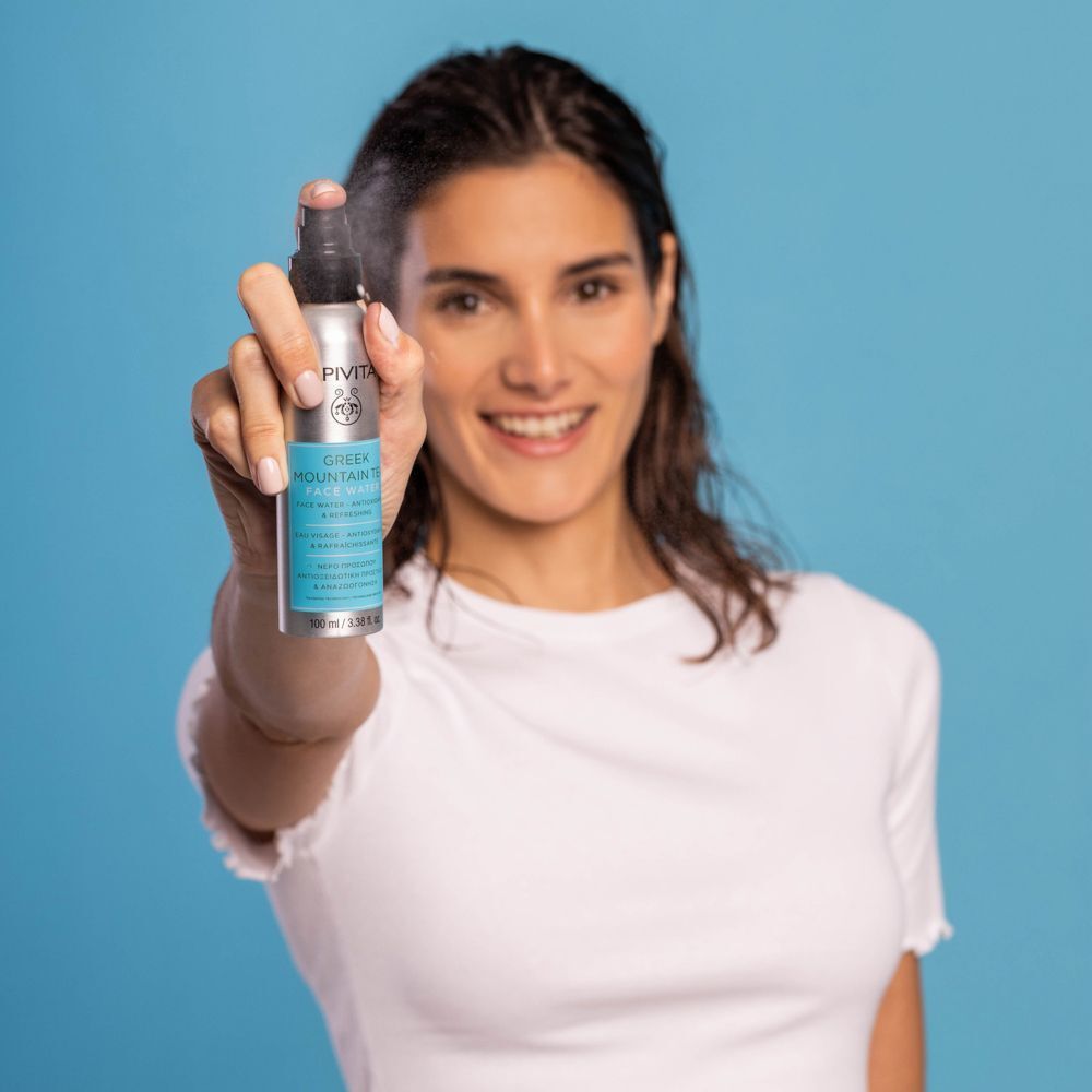 Donna con flacone spray di Acqua Viso APIVITA Tè Greco di Montagna.