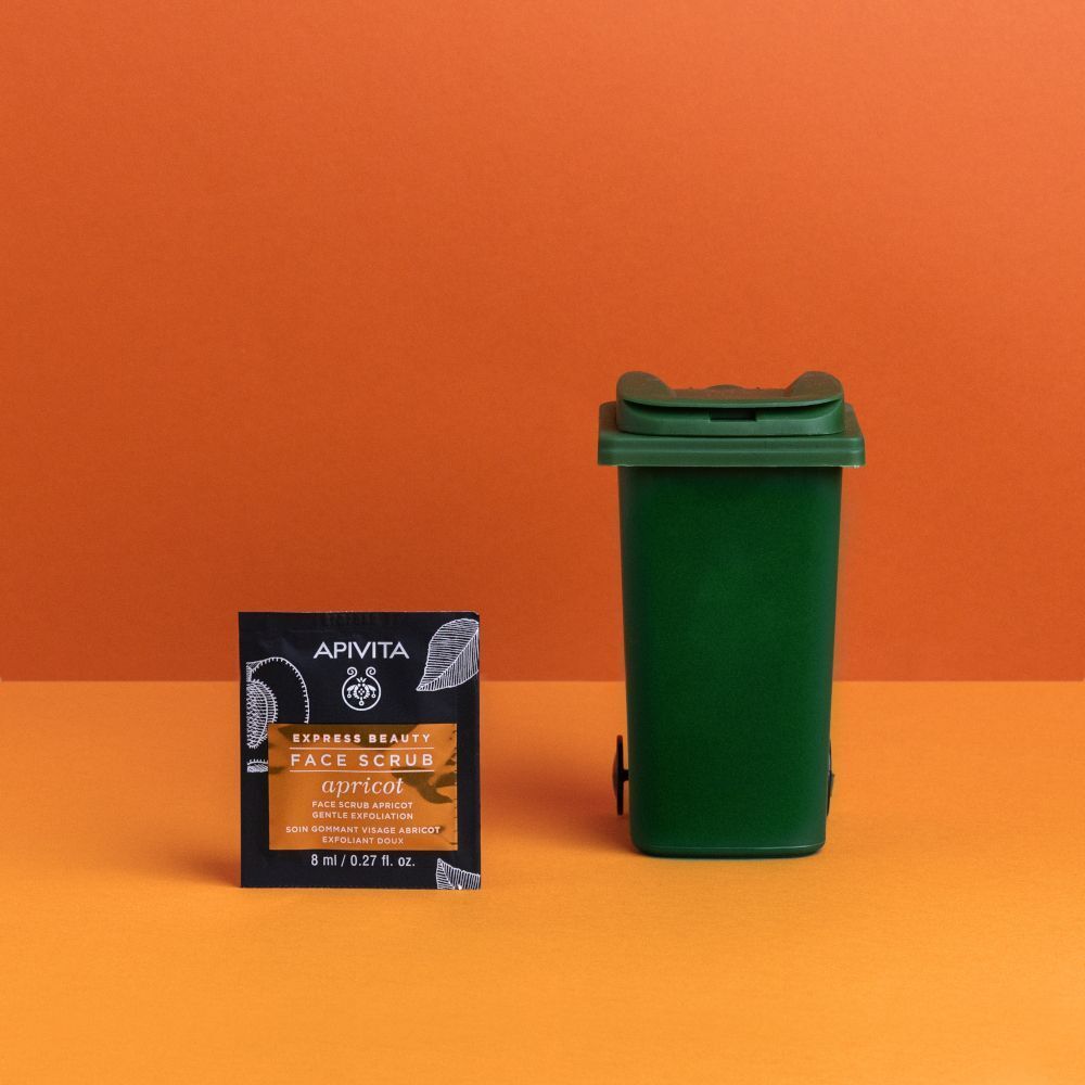 Una bustina APIVITA EXPRESS BEAUTY Scrub Viso con Albicocca accanto a un piccolo bidone verde.