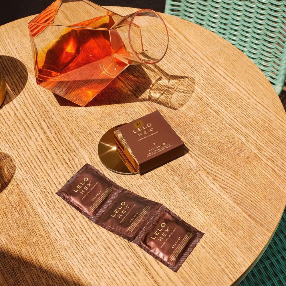 Tre Lelo HEX Preservativi Respect XL confezionati singolarmente su un tavolo di legno.