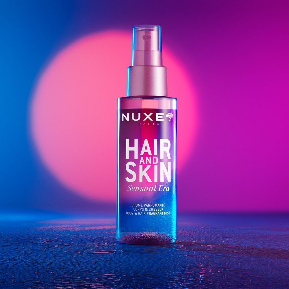Un flacone di Nuxe Hair and Skin Sensual Era Brume Profumante Corpo e Capelli su sfondo colorato.