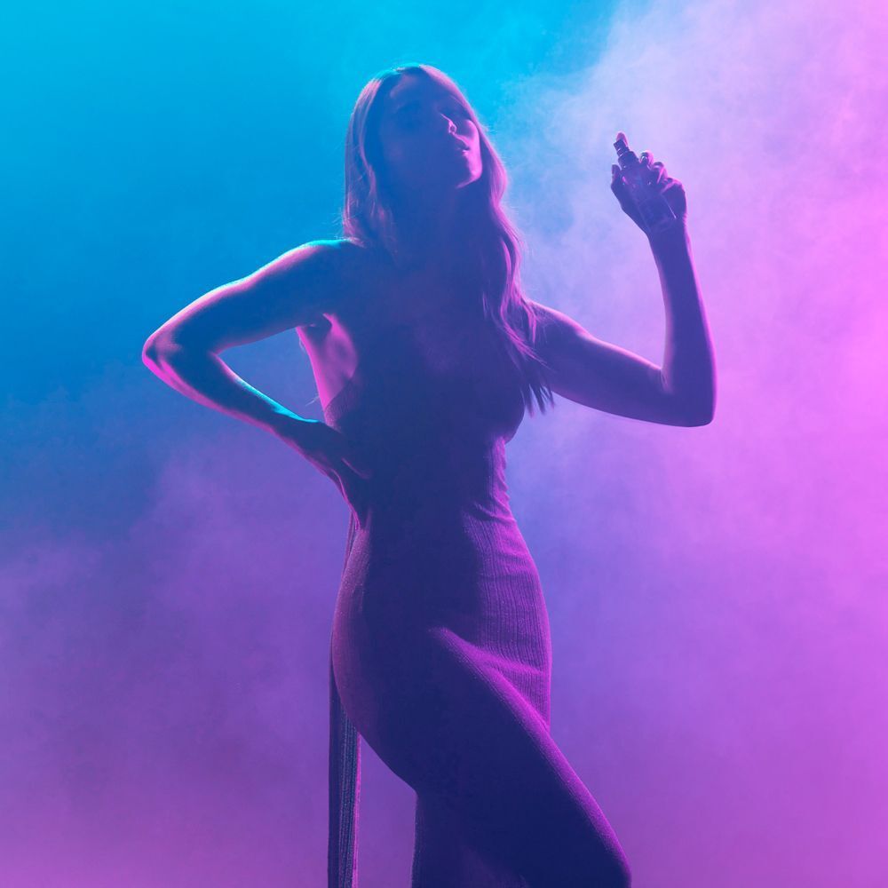 Silhouette di una donna che spruzza il profumo Nuxe Sensual Era nell'aria.