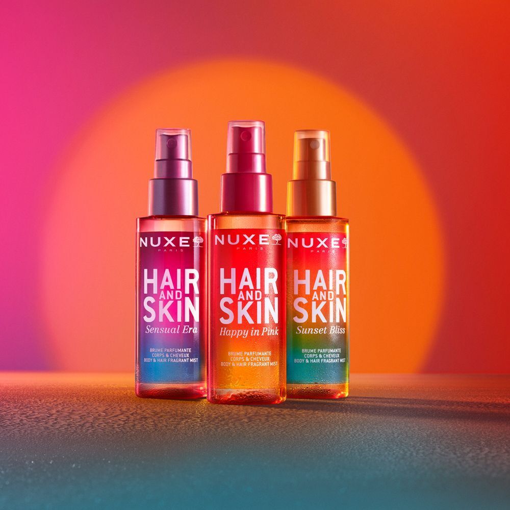 Tre flaconi di spray Nuxe Hair and Skin: Sensual Era, Happy in Pink, Sunset Kiss.