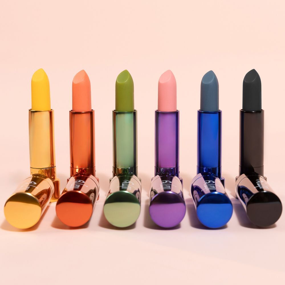Sei rossetti colorati nei loro contenitori. I colori sono giallo, arancione, verde, rosa, blu e nero.