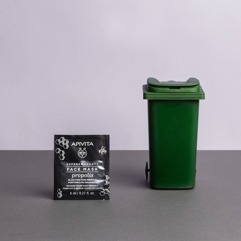 Maschera viso APIVITA EXPRESS BEAUTY Propoli, 8 ml, accanto a un cestino verde.