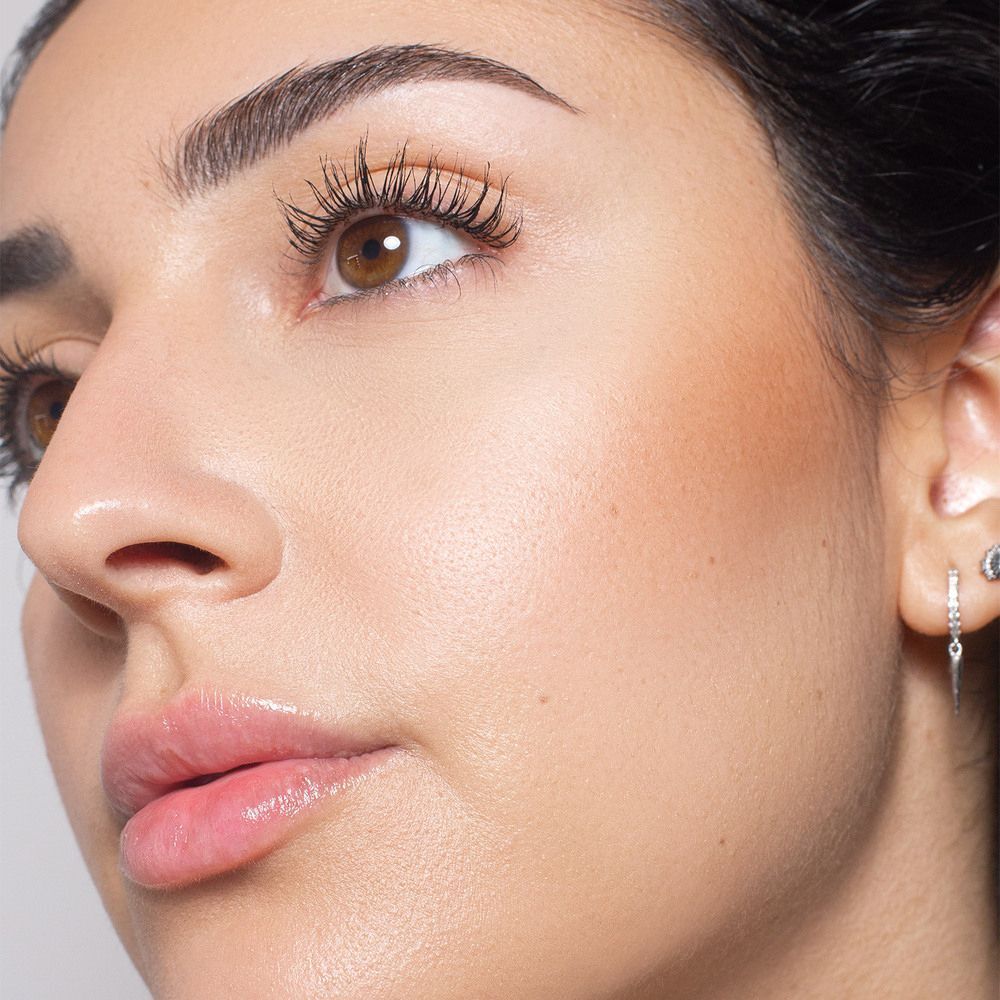Primo piano di una donna con cipria compatta ASTRA Bronze Skin Powder applicata.