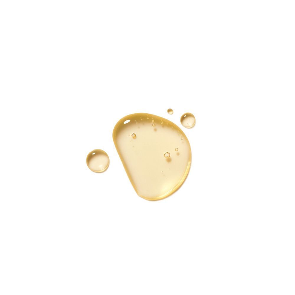 Una goccia di olio giallo con piccole bollicine e tre gocce più piccole accanto.