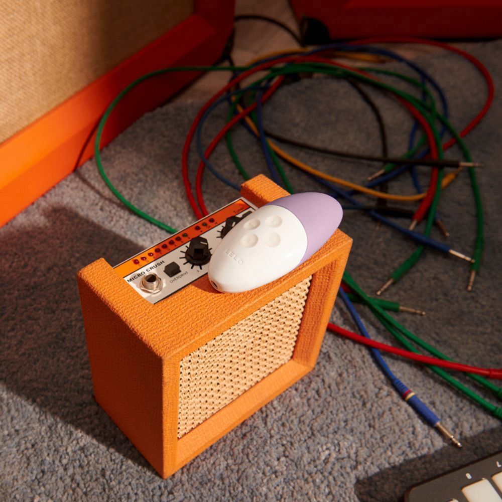 Vibratore lilla e bianco su un piccolo amplificatore arancione con cavi.