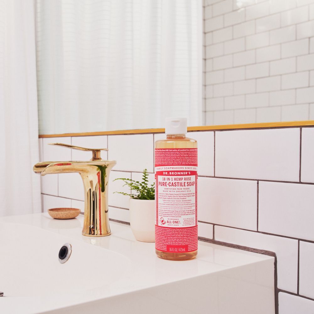 Un flacone di sapone liquido Dr. Bronner's 18-in-1 Rose su un lavandino vicino a un rubinetto.