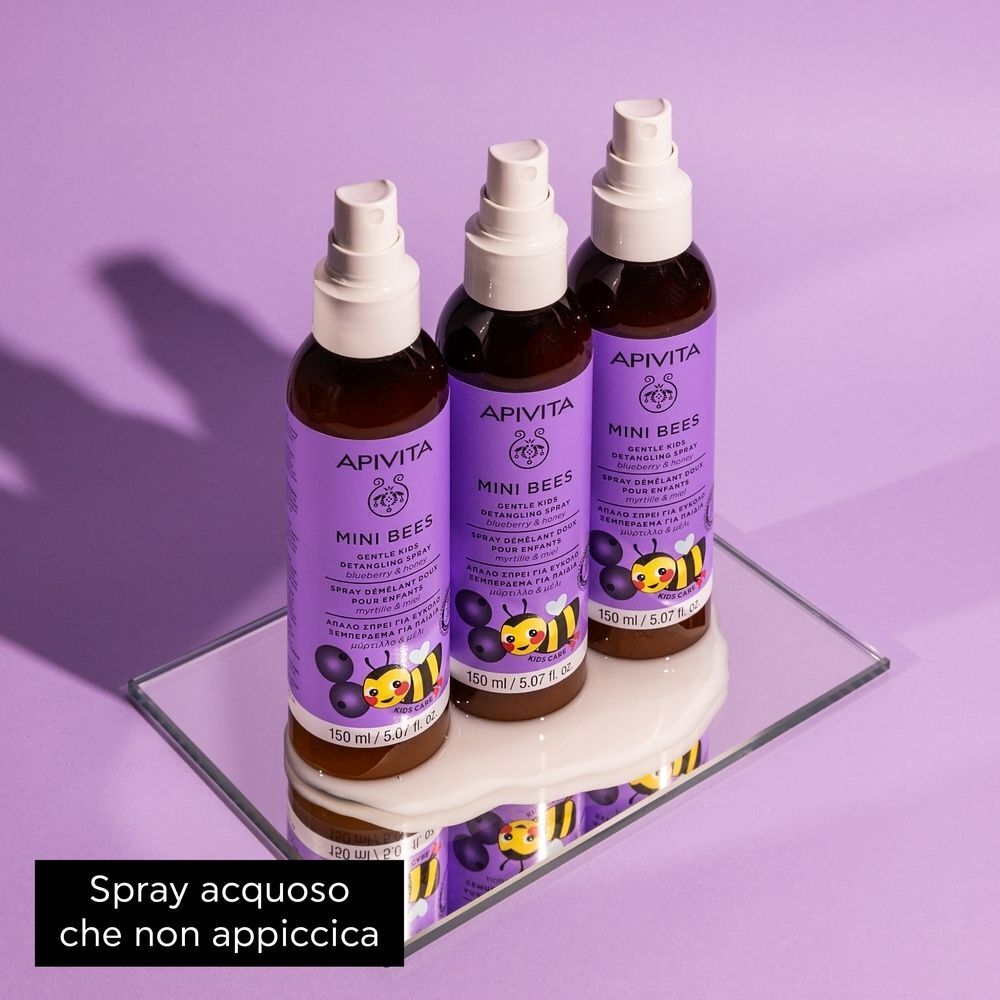 Tre flaconi di spray districante delicato per bambini Apivita Mini Bees su uno specchio.