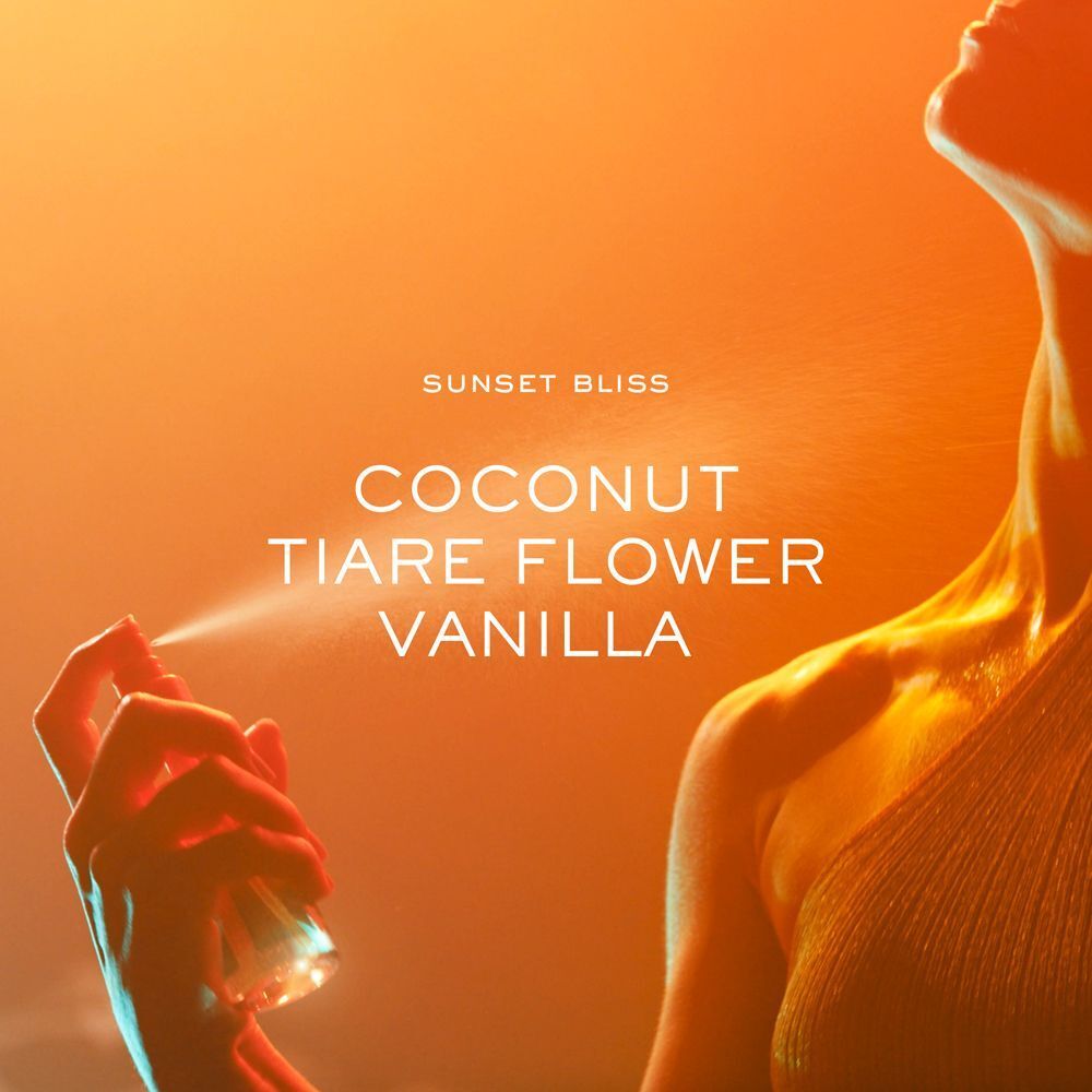 Donna che spruzza lo spray profumato Nuxe Sunset Bliss sulla pelle.