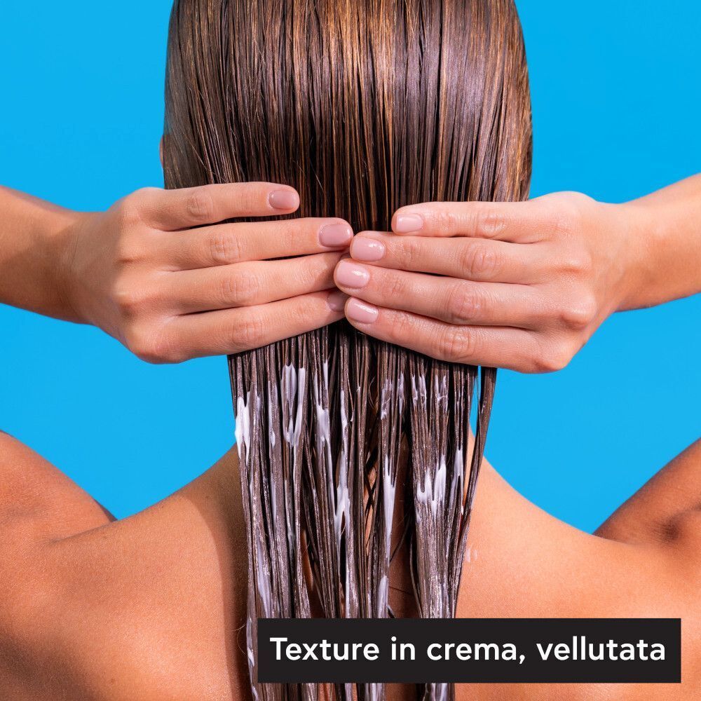 Mani applicano Apivita Hyaluronic Hydra Balsamo su capelli bagnati.
