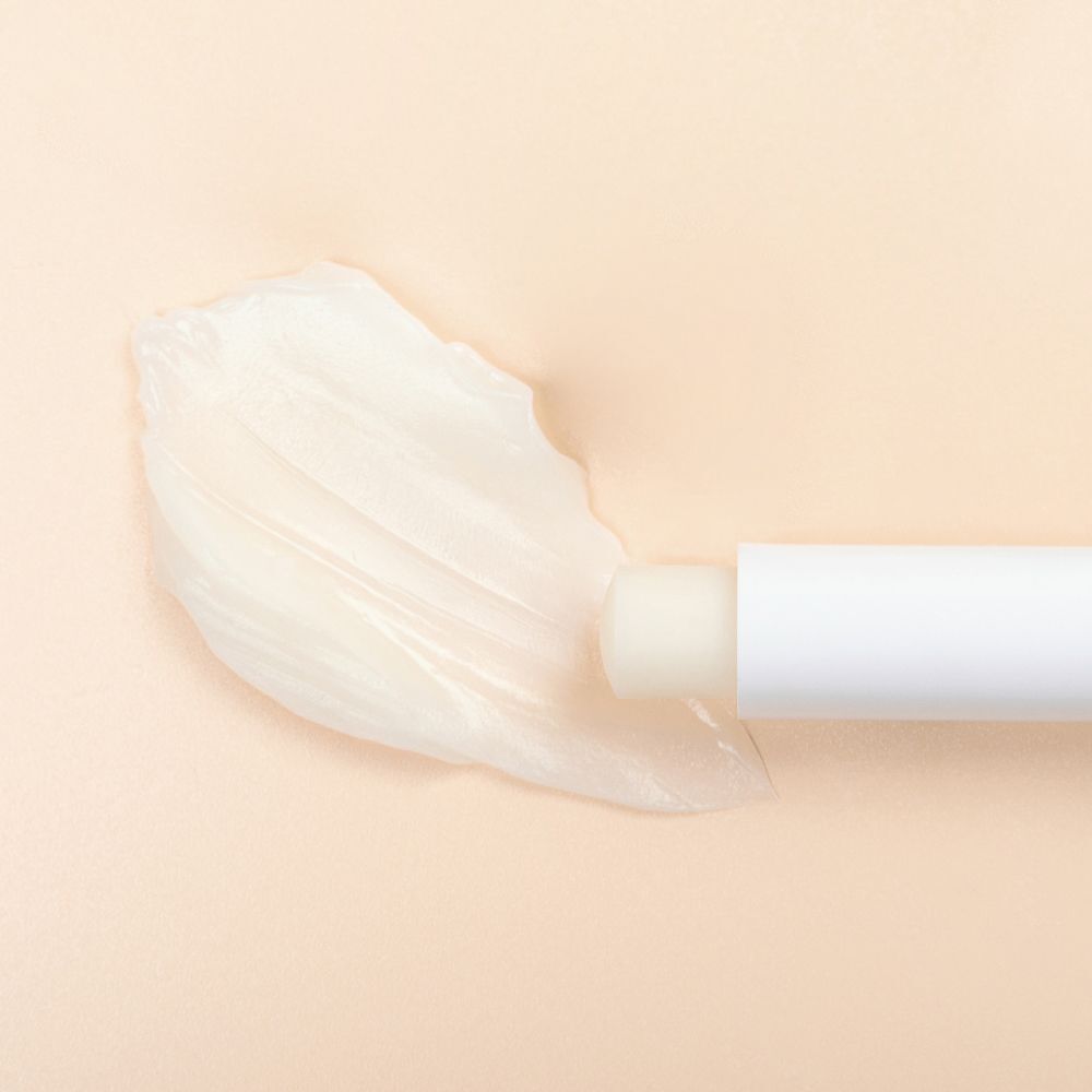 Un stick LEPO Lip Remedy bianco con balsamo applicato.