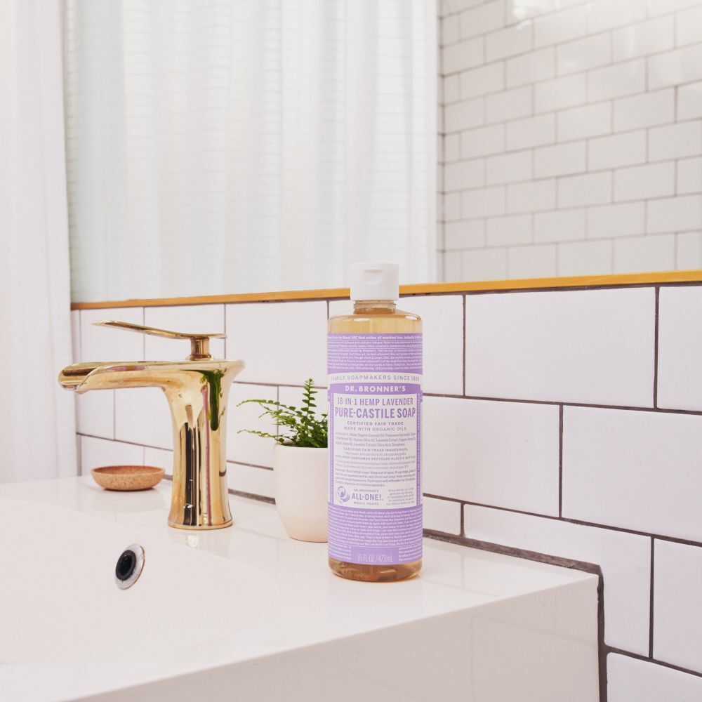 Sapone liquido Dr. Bronner's Lavanda sul bordo di un lavandino accanto a una pianta.