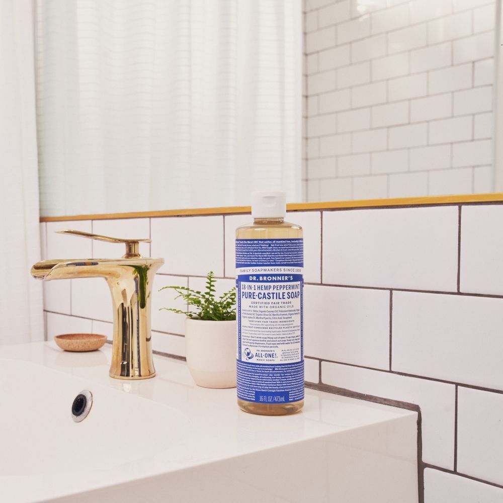 Sapone liquido Dr. Bronner's menta piperita vicino a un rubinetto su un lavandino.
