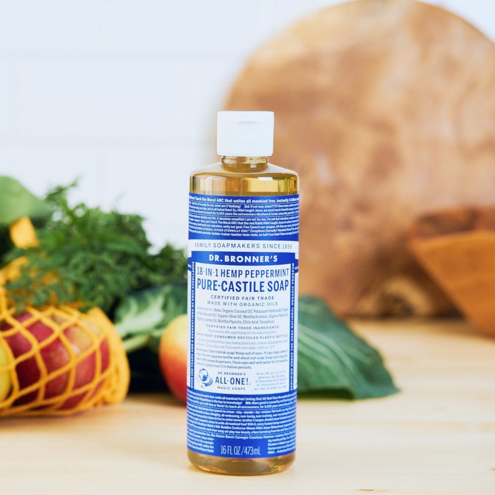 Flacone di sapone Dr. Bronner's menta piperita vicino a frutta e verdura fresca.