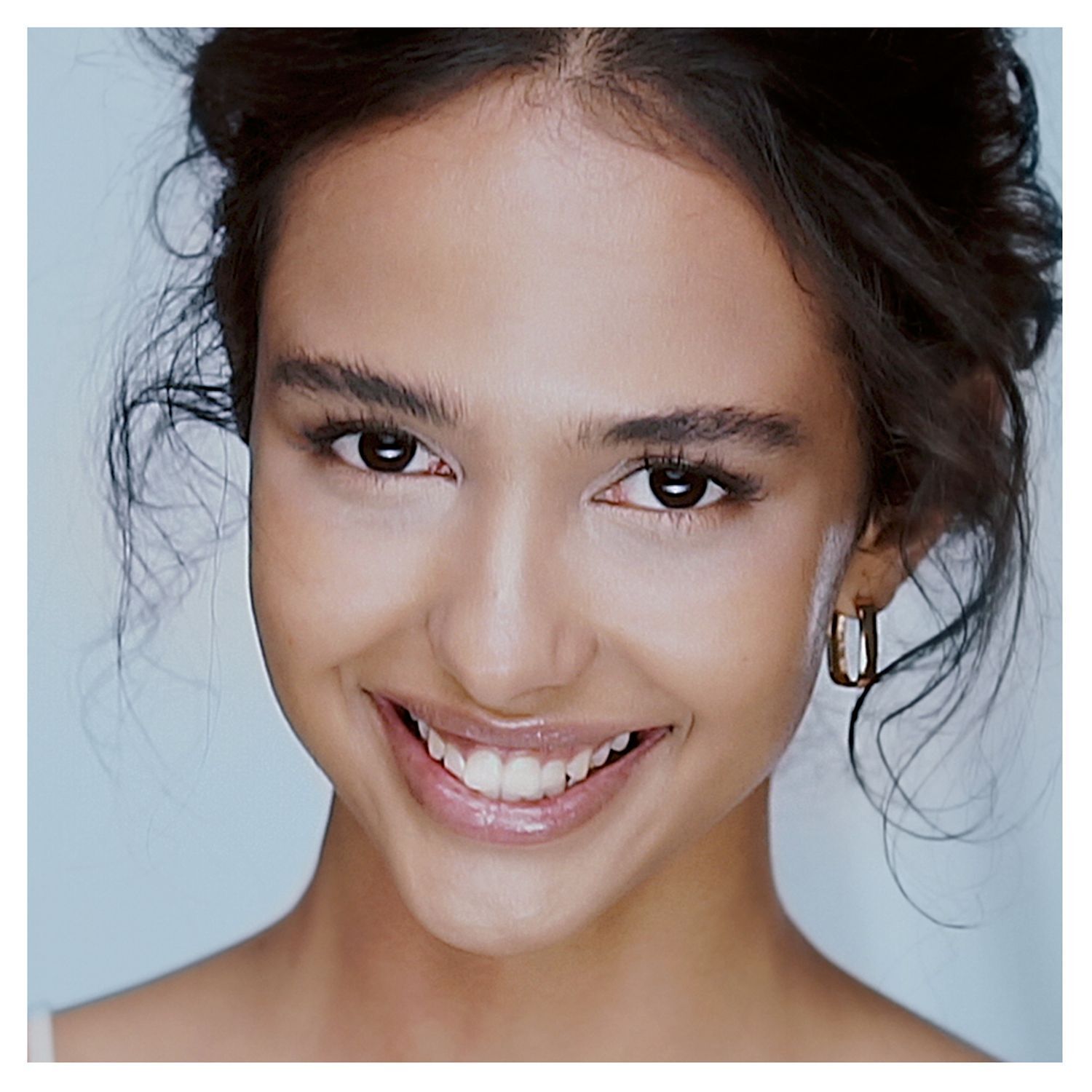 Ritratto di una giovane donna sorridente, capelli sciolti, con orecchini.
