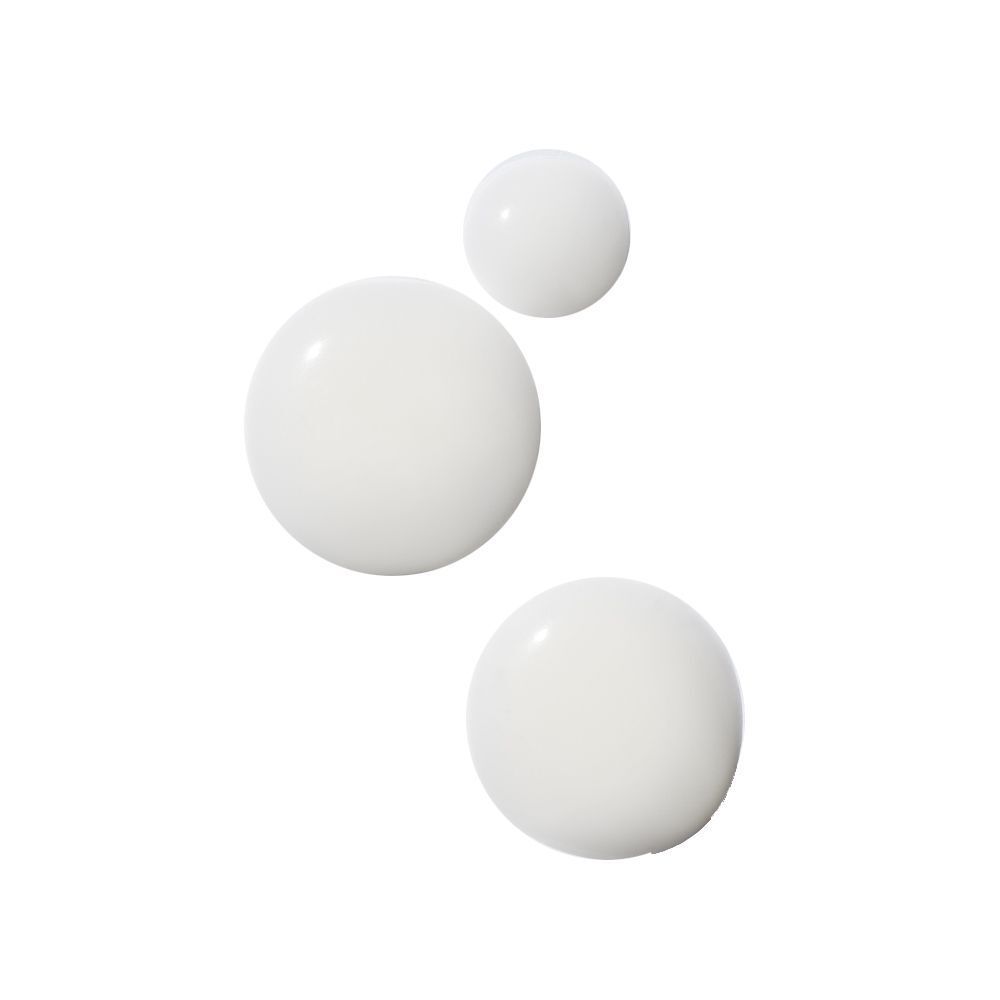 Tre gocce di liquido bianco su sfondo bianco.