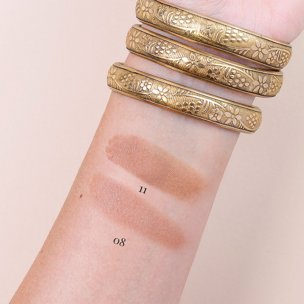 Swatch di bronzer sulla pelle, Nuance 11 e 08, con bracciali dorati.
