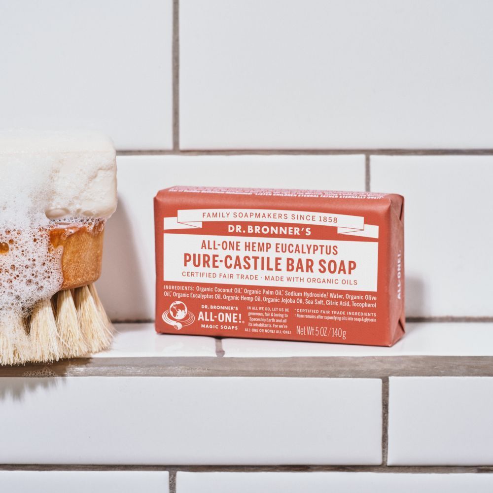 Sapone Dr. Bronner's All-One Eucalyptus Pure-Castile Bar Soap (140g) accanto a una spazzola bagnata con schiuma.