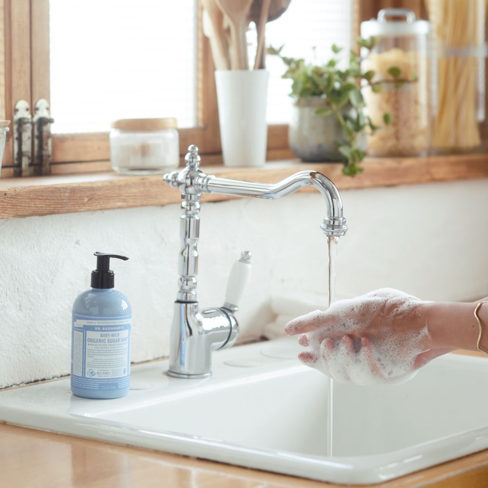Sapone biologico allo zucchero Dr. Bronner's accanto a un rubinetto mentre ci si lava le mani.