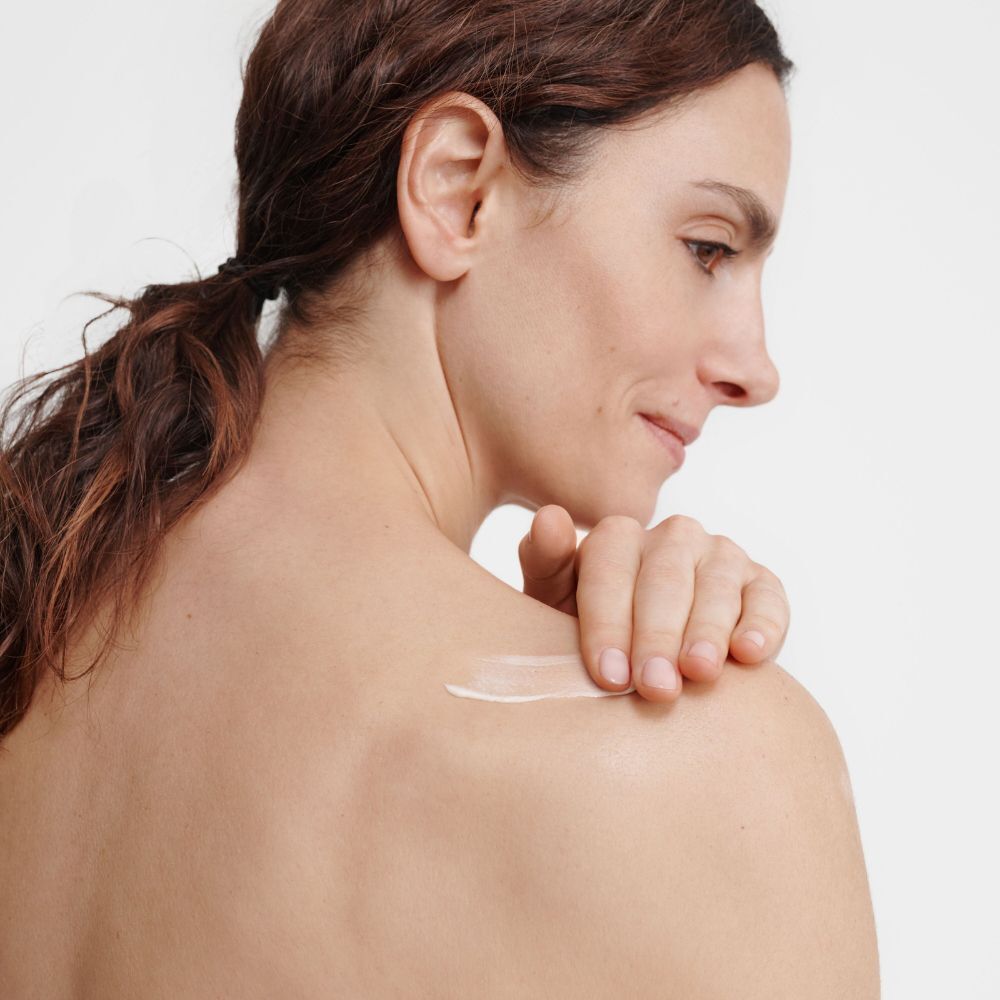 Una donna si applica una crema sulla spalla.