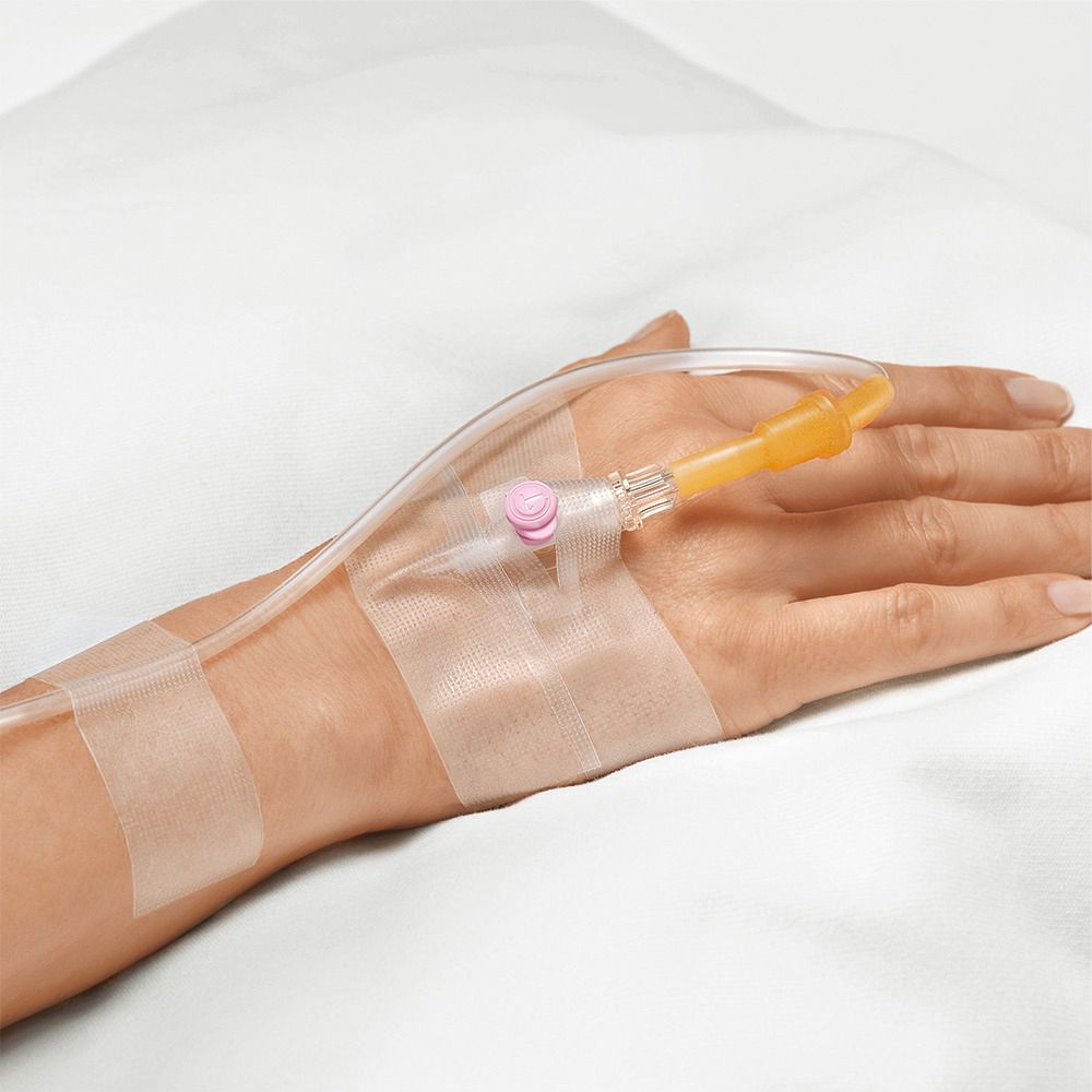 Mano con catetere endovenoso. Nastro adesivo fissa il catetere. Su sfondo bianco.