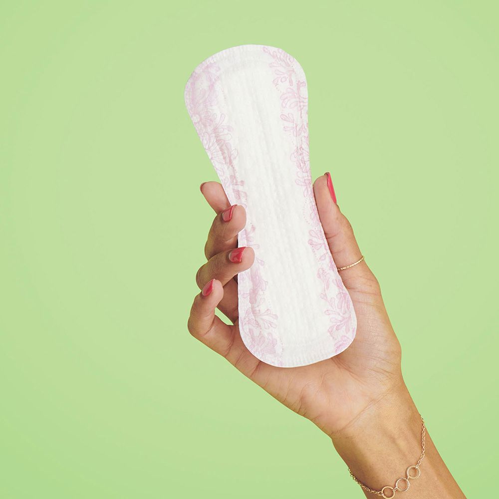 Prodotto bianco e allungato, tenuto in mano. Motivo rosa sulla superficie. Sfondo verde.